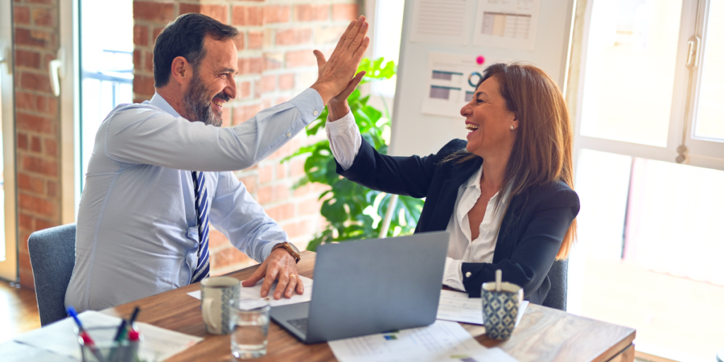 Man and woman high fiving in office