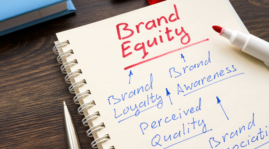 Notebook that says "Brand Equity" with the words "Brand Loyalty," Brand Awareness," "Perceived Quality," and Brand Association" written under it with arrows all pointing back to it.
