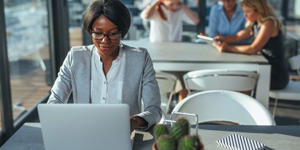 A woman sits at a table writing a business blog as part of her inbound marketing strategy, illustrating one of the many benefits of inbound marketing in that business blogging helps attract visitors to your website.