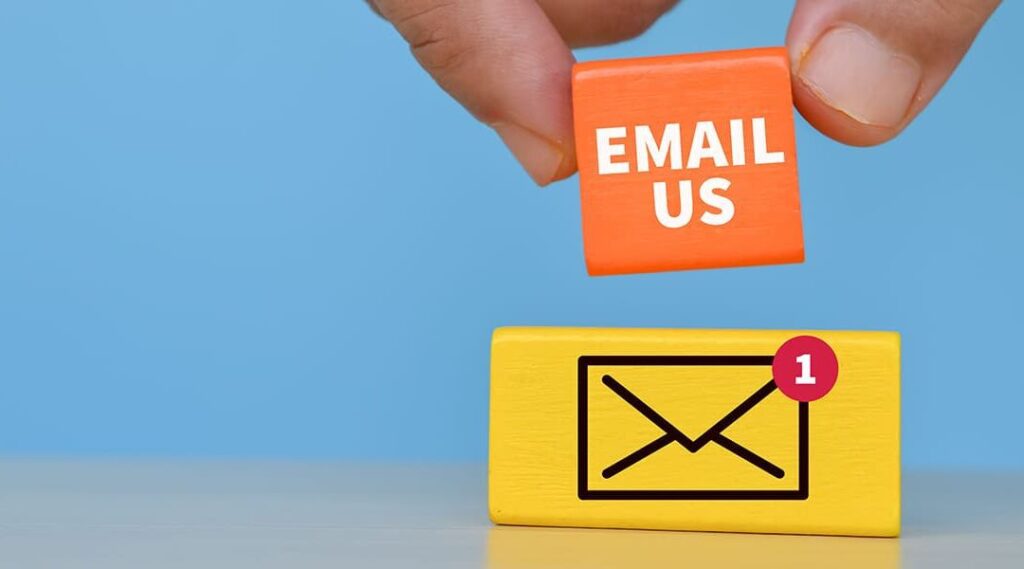 fingers holding orange block that says email us over yellow block with email symbol