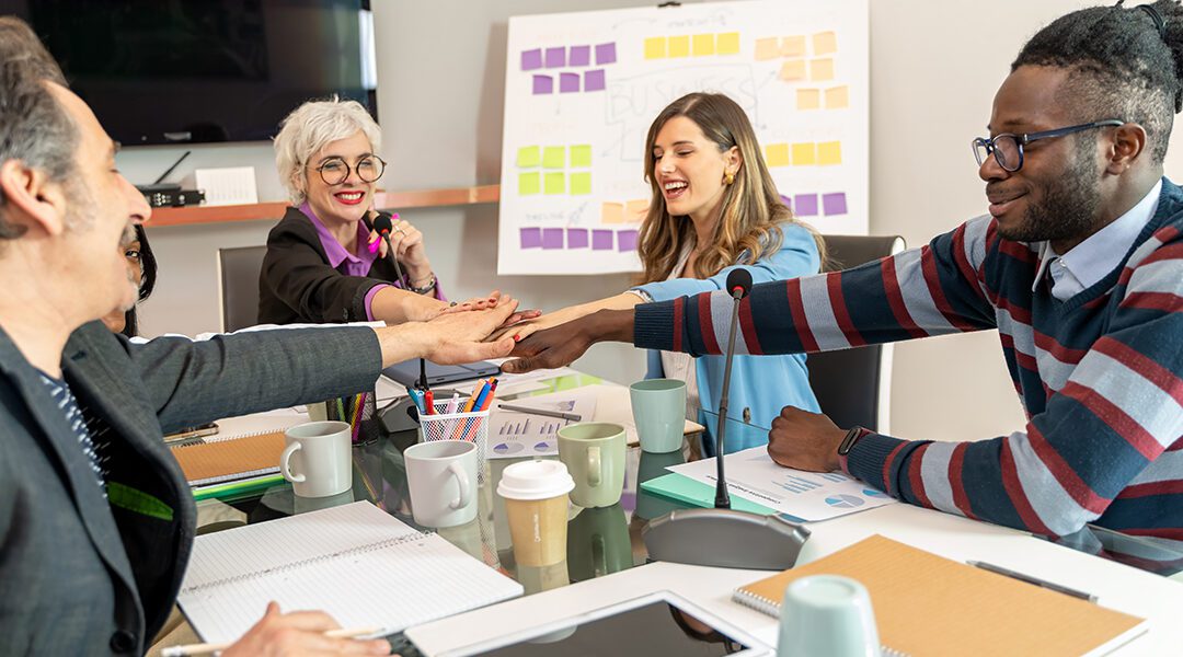 Modern office team with their hands in over the table to celebrate