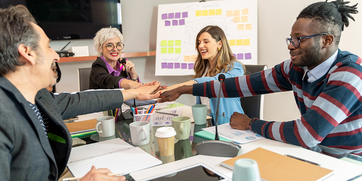 Modern office team with their hands in over the table to celebrate