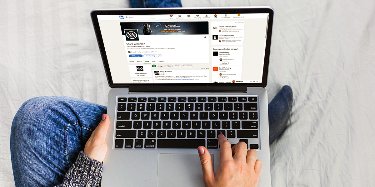 person sitting on bed with LinkedIn pulled up on their laptop screen
