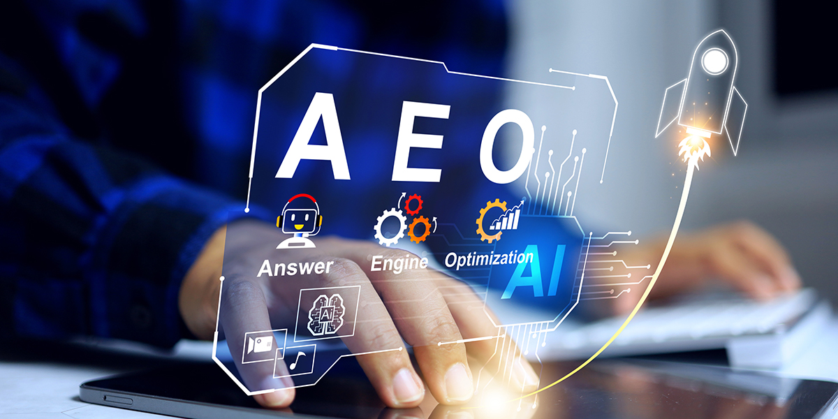 Close-up of a hand touching a tablet with holographic AI graphics labeled AEO, gears, and a launching rocket to symbolize AI-powered optimization.